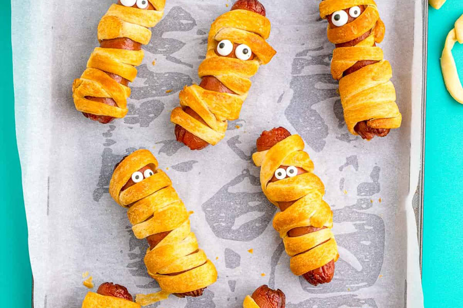 Halloween Party Food Ideas for Kids Mummy Hot Dogs on a Baking Sheet with Parchment Paper