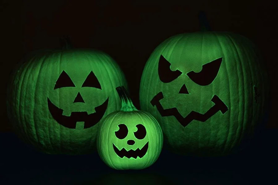 Pumpkin Carving Ideas for Halloween Three Carved Pumpkins Glowing Green in a Dark Room